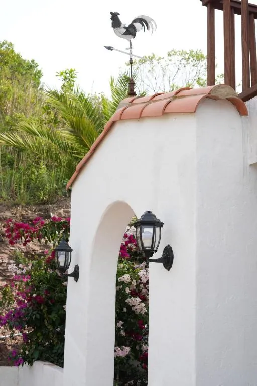 Arco blanco con veleta de gallo y buganvilias