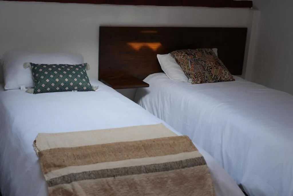 Camas sencillas con cobijas de lana en un cuarto de la casa