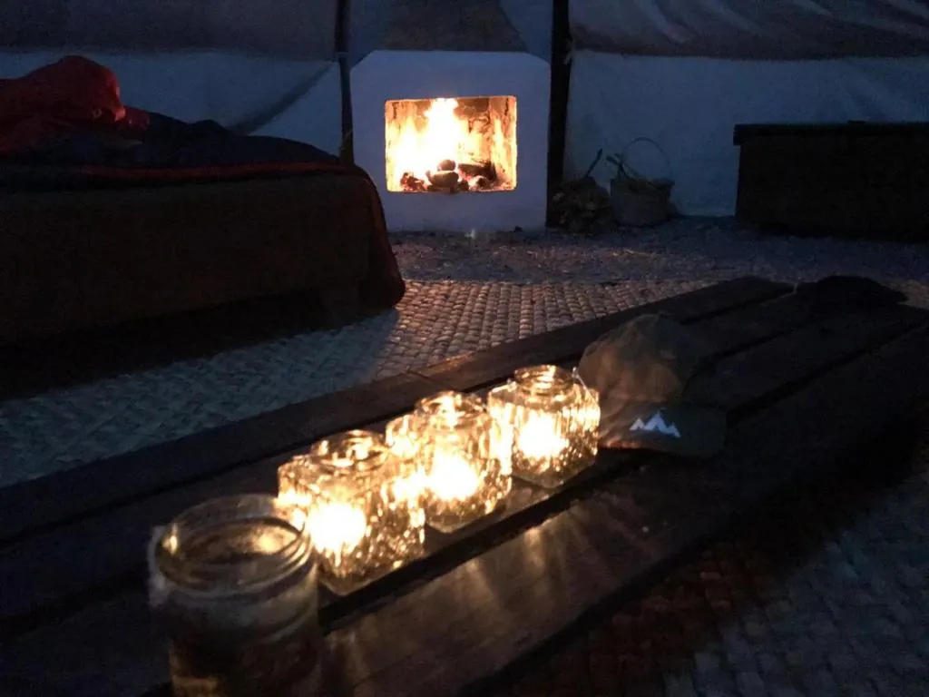 Chimenea encendida dentro del tipi, con velas sobre la mesa