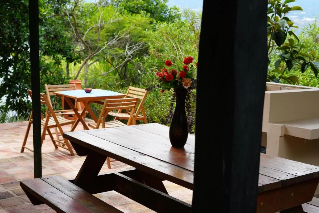 Mesa de madera con flores en la terraza, entre árboles y montaña