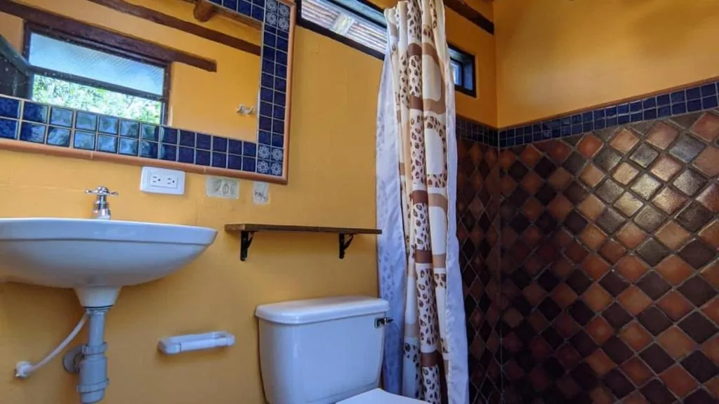Baño con lavamanos, enchape de cerámica y ducha