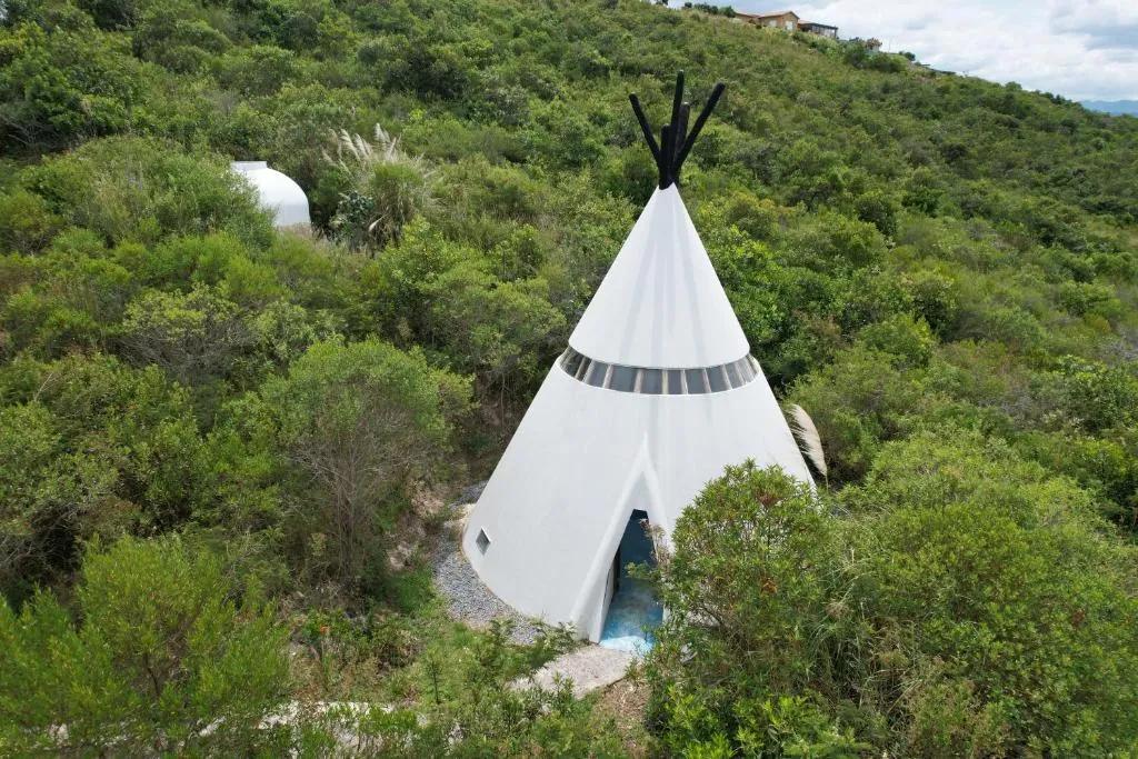 Tipi blanco en medio del monte verde, visto desde arriba
