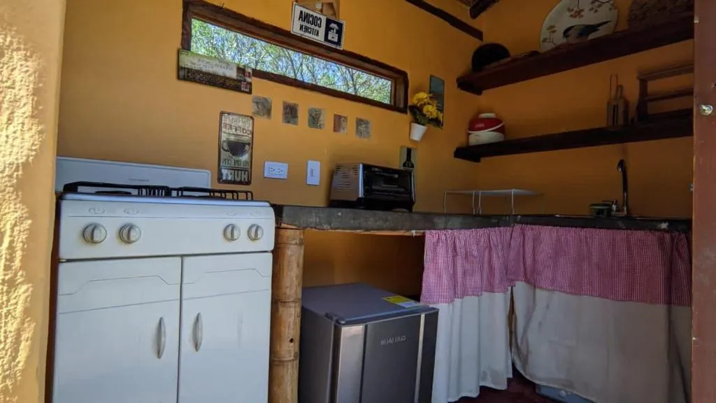 Cocina amarilla con estufa, nevera y estantes de madera